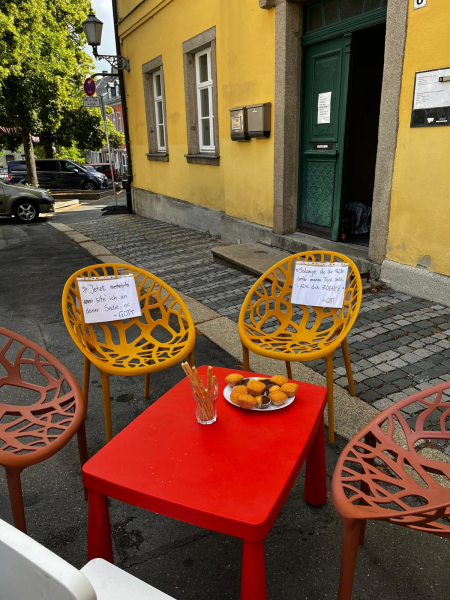 Caféstühle auf Platz vor gelbem Haus
